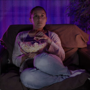 Woman relaxing at home with popcorn in front of the TV.
