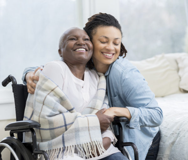 Young woman embraces her beautiful senior mother who is in a wheelchair.