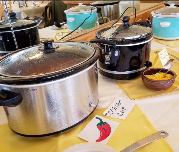 three pots of chili sitting on table at a chili competition